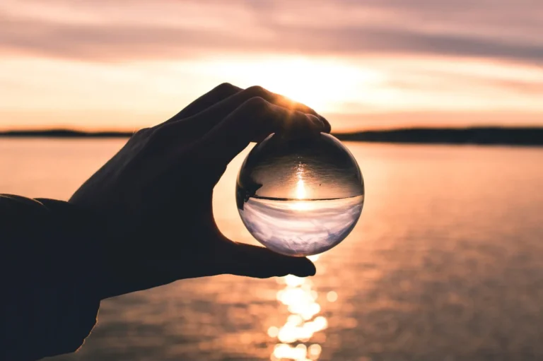 sunset over a body of water with a glass ball as the focal point